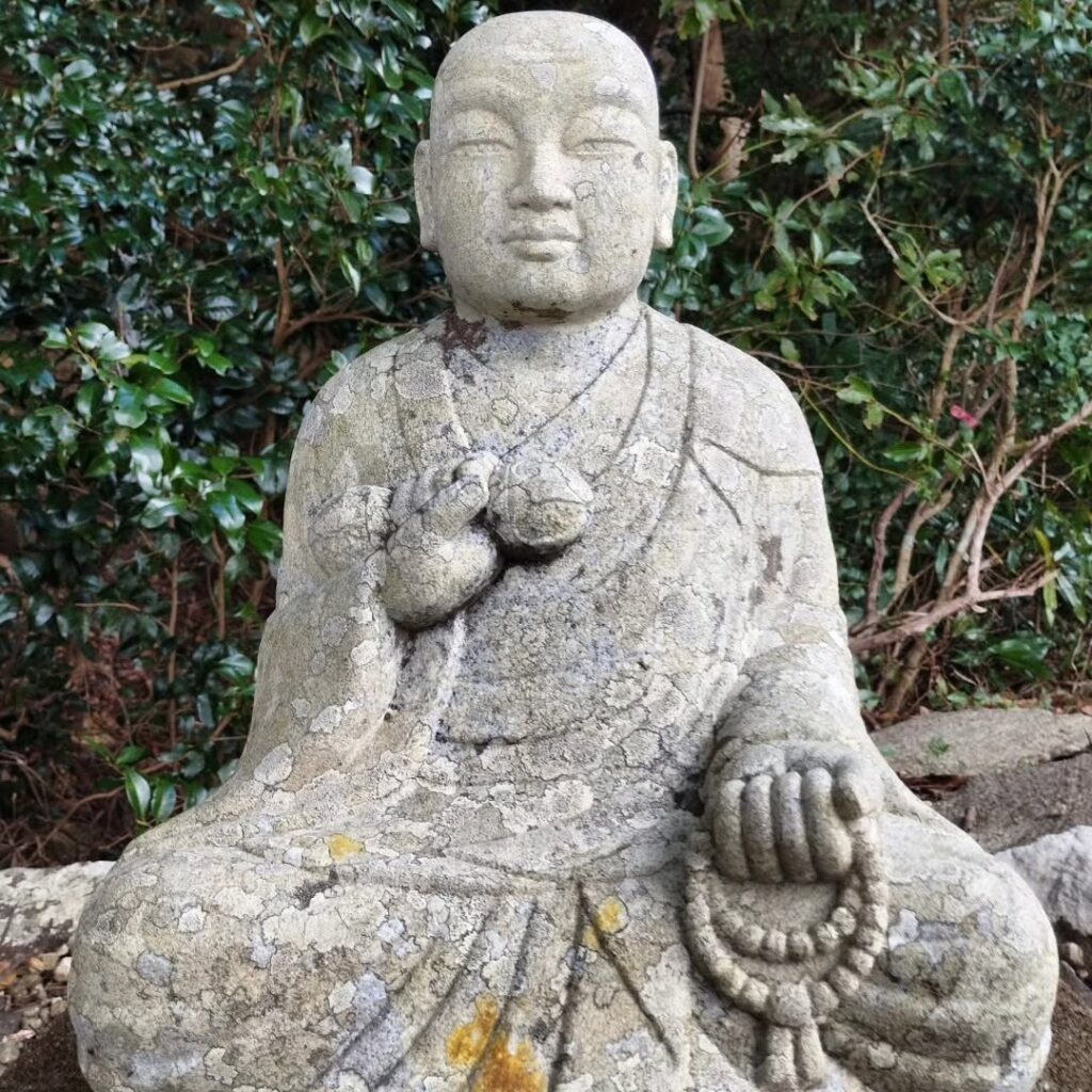 A statue of Kukai holding a nenju, Buddhist prayer beads, in his left hand.