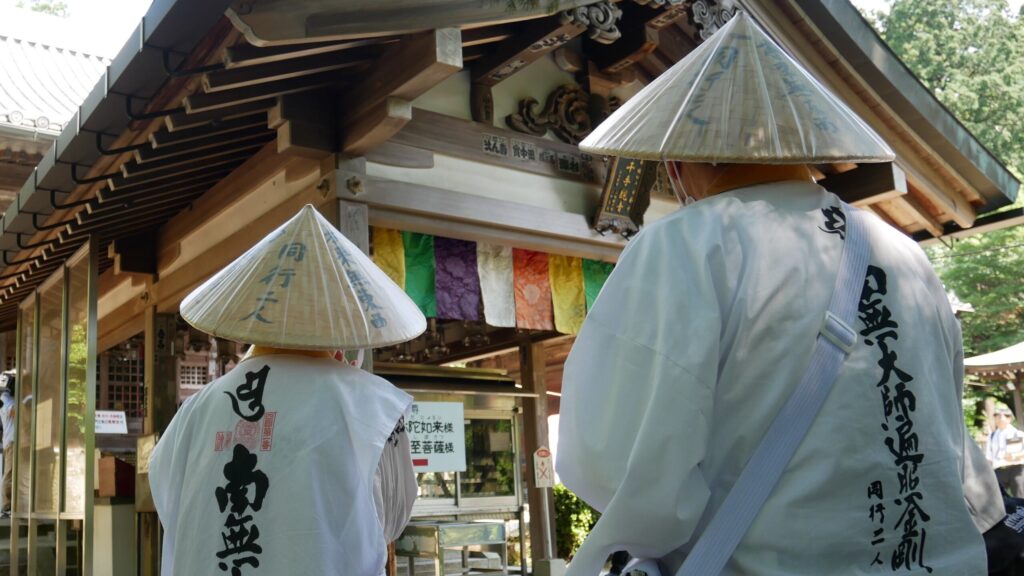 Two pilgrims in traditional garb prepare to offer prayers at the main hall of Temple 81, Shiromine-ji.