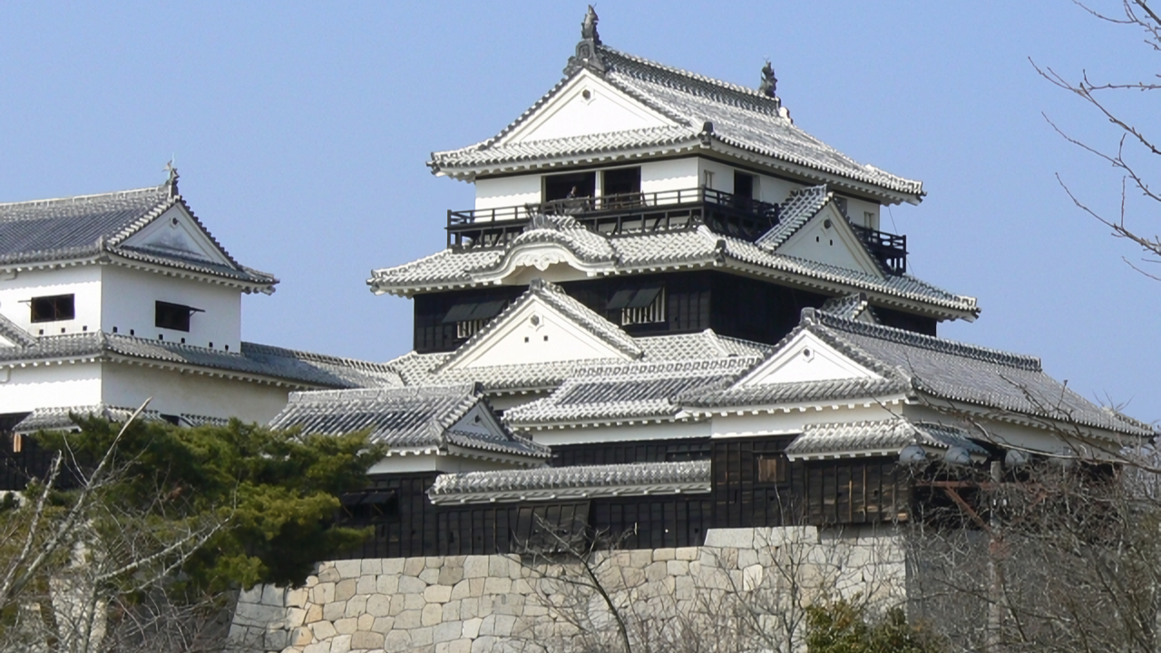 The main keep of Matsuyama Castle against a blue sky.
