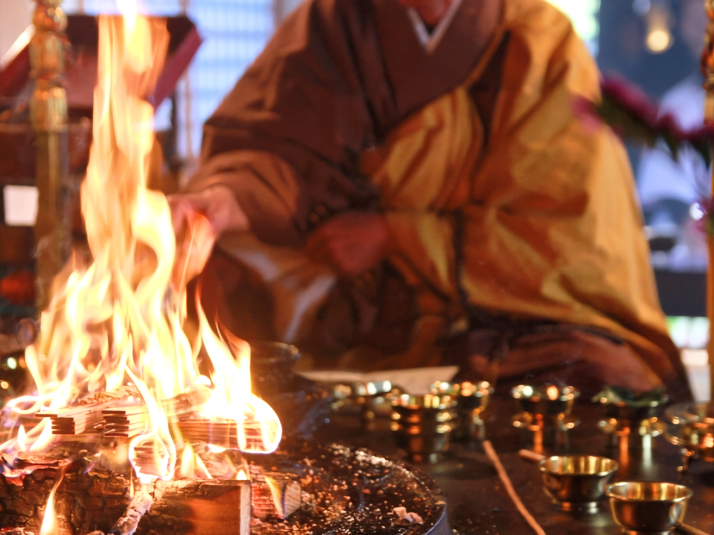 A priest feeds wooden prayer tablets (gomagi) into the ritual fire. Each tablet carries the prayers and wishes of devotees, which are believed to be carried to the Buddha through the flames.