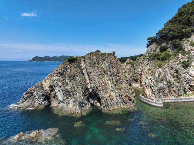 Vertical geological strata at Suzaki Coast in Seiyo, Ehime. Massive rock cliffs rising from the highly transparent, emerald green sea.