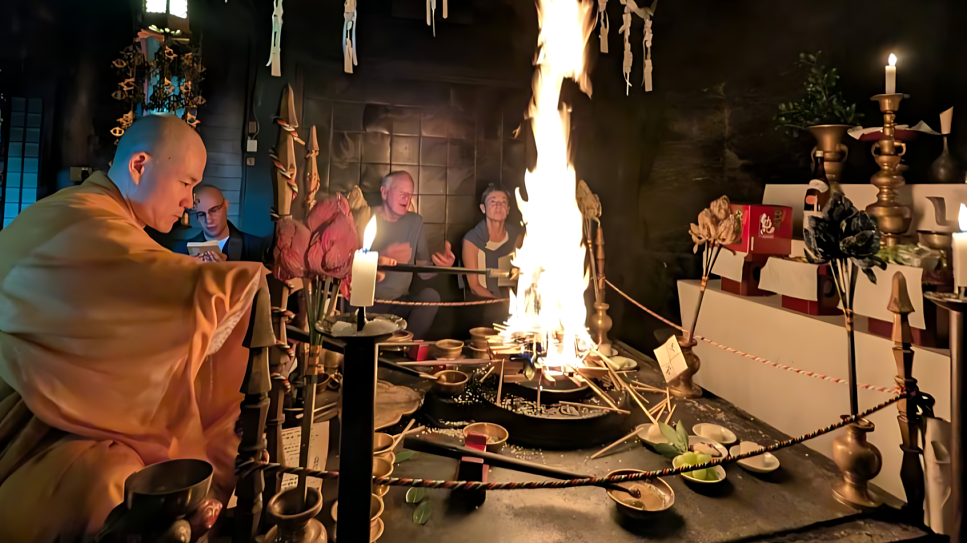 A candid photograph capturing a sacred Japanese Buddhist fire ceremony (Goma) in a dimly lit temple