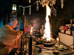 A candid photograph capturing a sacred Japanese Buddhist fire ceremony (Goma) in a dimly lit temple