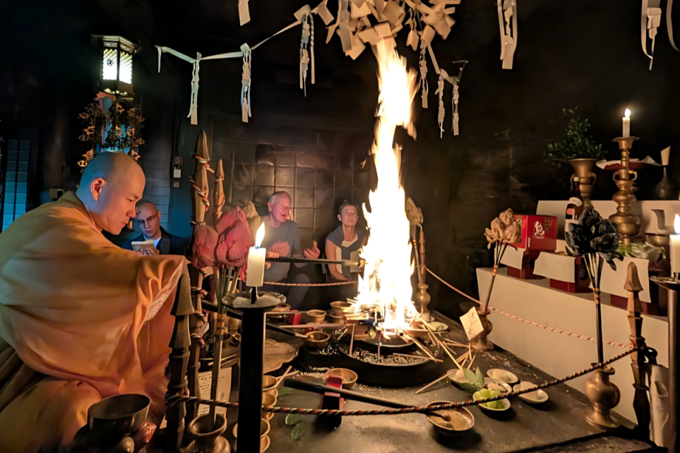 A candid photograph capturing a sacred Japanese Buddhist fire ceremony (Goma) in a dimly lit temple