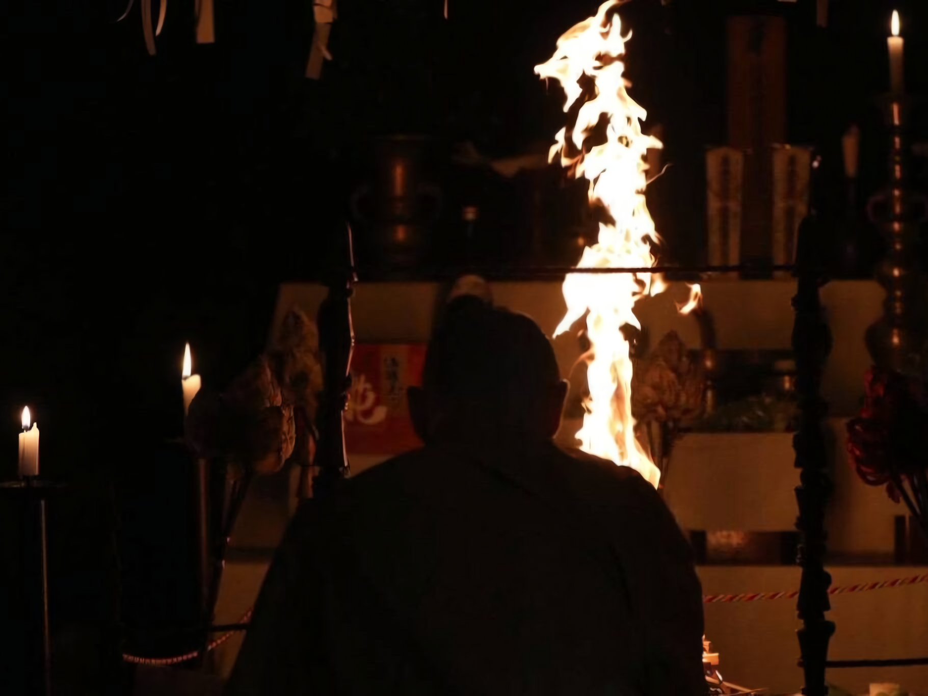 An intimate, atmospheric photograph capturing a traditional Japanese Buddhist Goma fire ritual.
