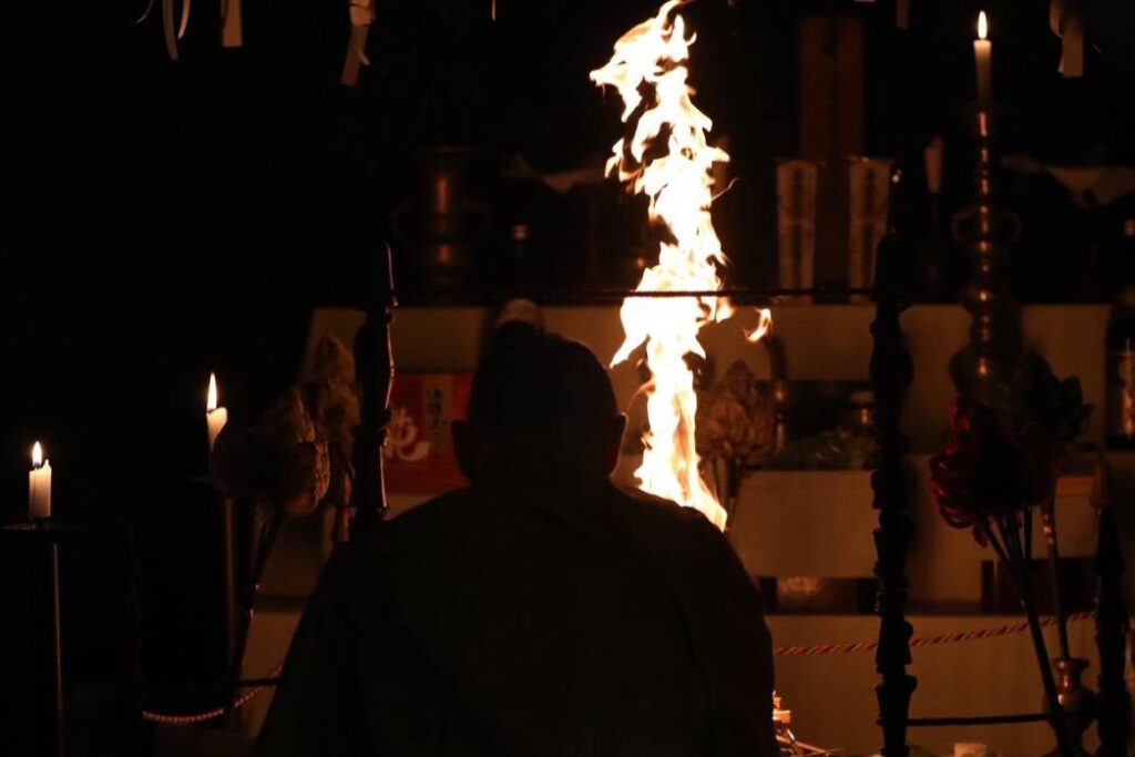 An intimate, atmospheric photograph capturing a traditional Japanese Buddhist Goma fire ritual.