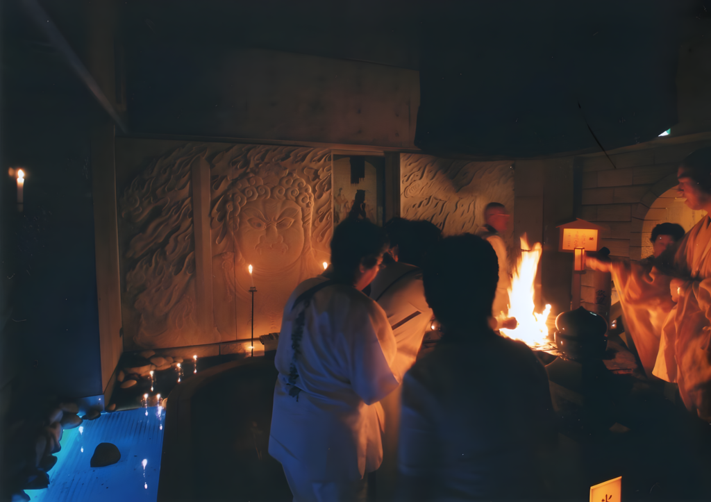 A detailed interior view of a dimly lit Japanese Buddhist temple during a traditional Goma fire ritual.