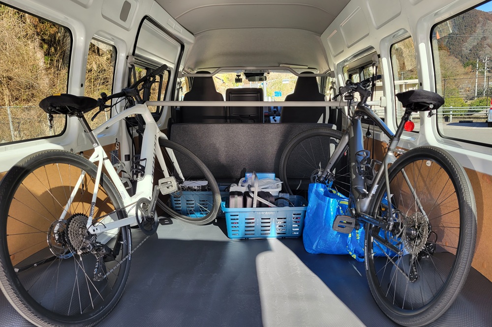 Interior view of a support van with two gravel bikes secured and organized supplies.