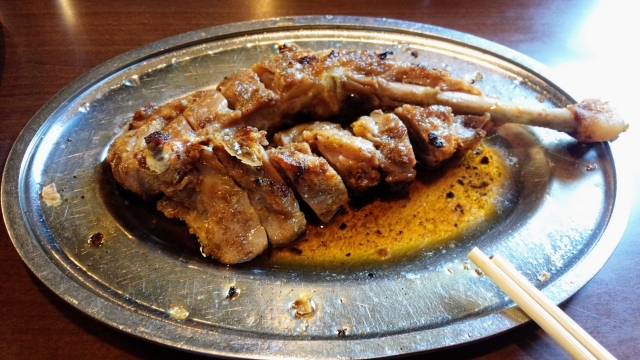 Honetsukidori, a famous Japanese roasted bone-in chicken thigh dish from Kagawa, served on a metal plate.