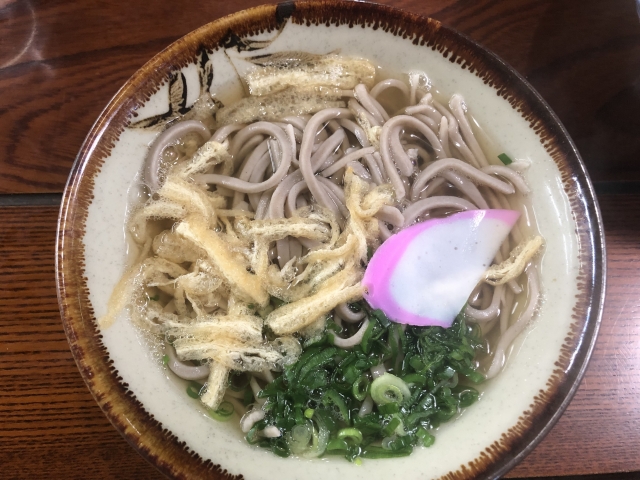 A bowl of traditional Tokushima Iya Soba noodles topped with fried tofu, kamaboko fish cake, and green onions.