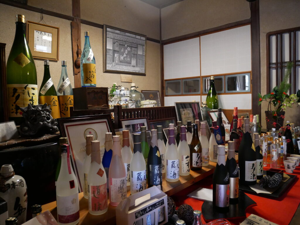 A display of various regional sake bottles inside the traditional Minakuchi Shuzou brewery shop in Dogo, Matsuyama.