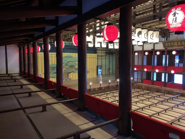 The atmospheric interior of the theater viewed from the upper tatami seating, showing the traditional grid-style floor.