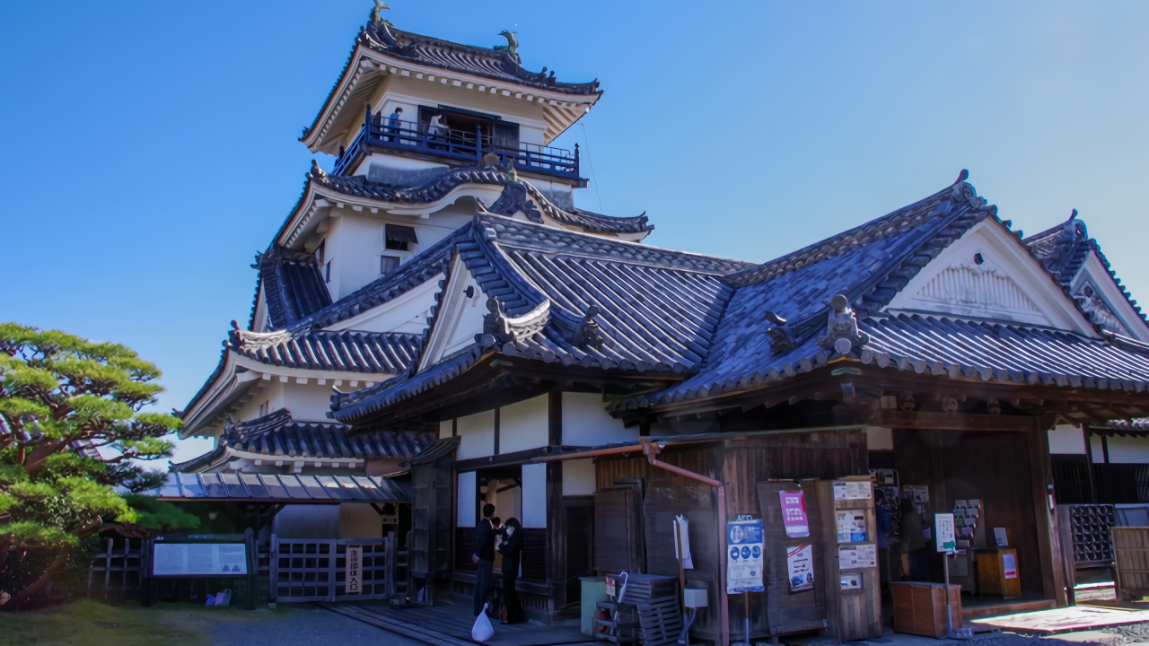 This photo features Kochi Castle's historic main tower and its connected traditional palace entrance under a beautiful clear blue sky.