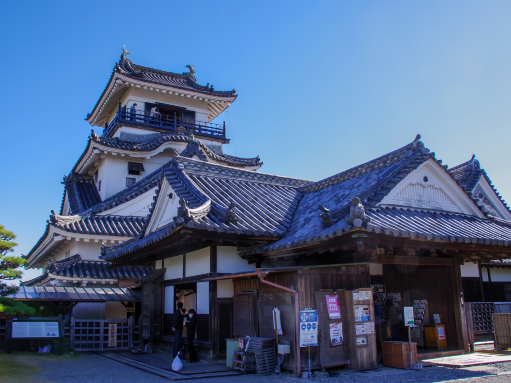 This photo features Kochi Castle's historic main tower and its connected traditional palace entrance under a beautiful clear blue sky.