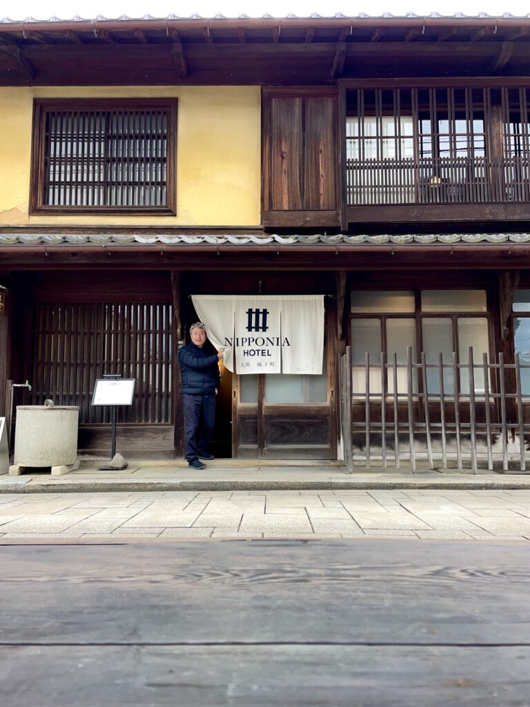 A visitor emerges from a historical building in Ozu, renovated into luxury accommodation.