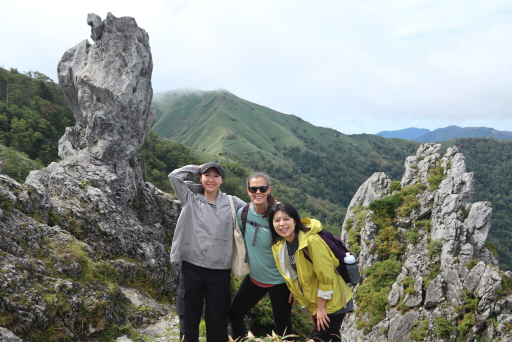 Visitors smile in front of Mt. Tsurugi's dramatic sacred rock formations.