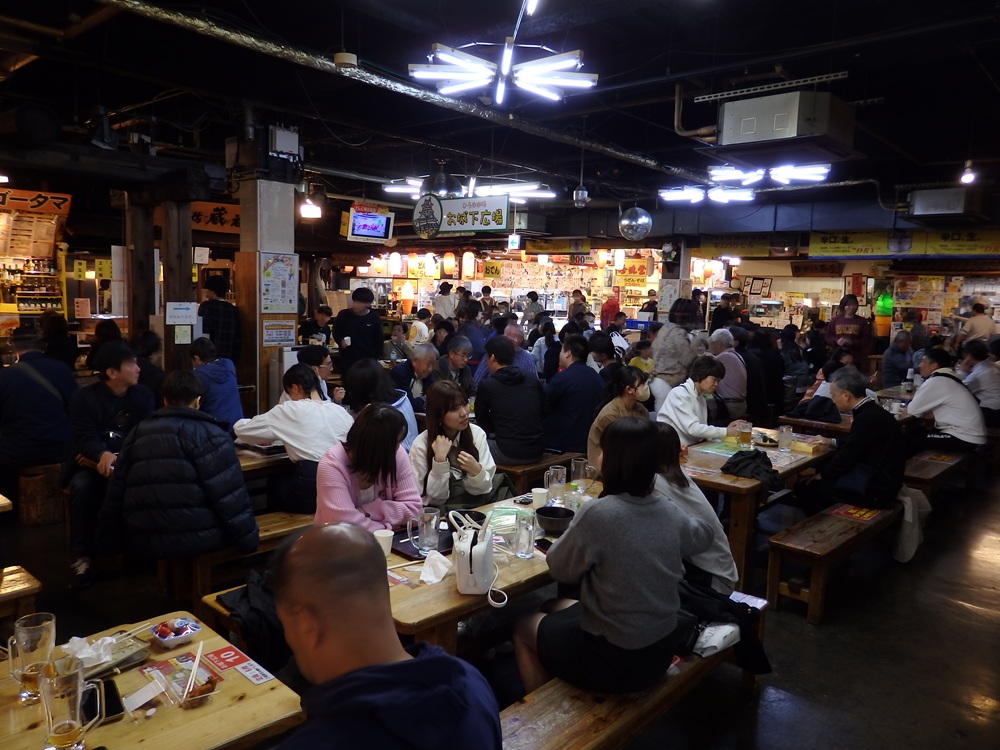 A bustling indoor dining area crowded with people at Hirome Market.