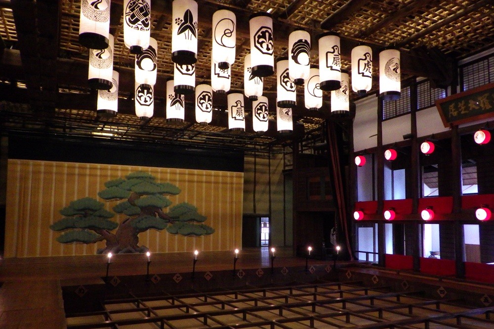 The authentic Edo-period stage featuring a classic pine tree backdrop under a ceiling of elegant paper lanterns.
