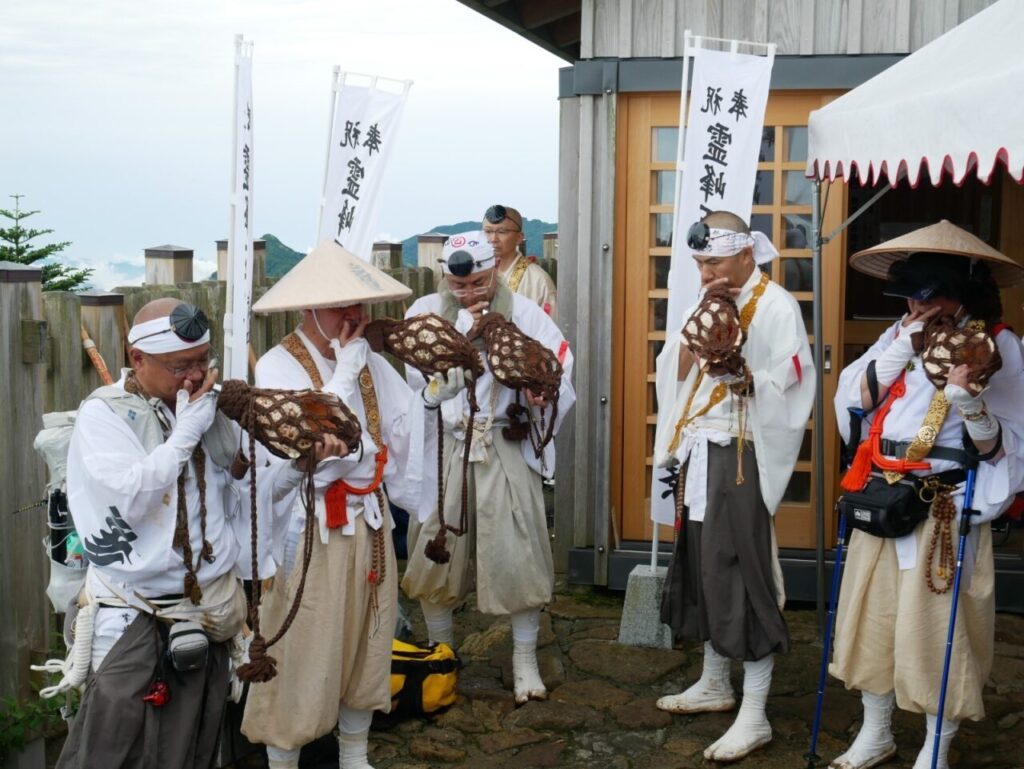 Shugendo Practitioners, or "Yamabushi," blow conch shells at the mountaintop shrine on Mt. Ishizuchi