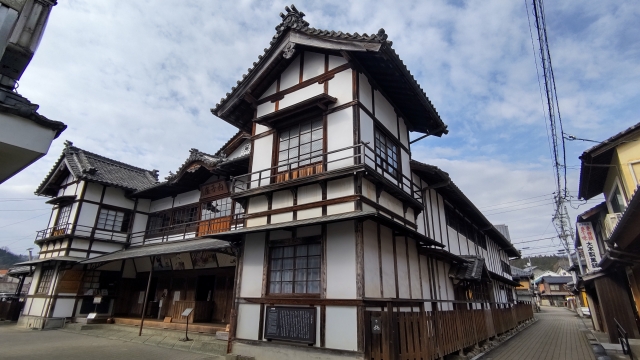 This wide shot showcases the magnificent two-story exterior of Uchikoza Theatre, featuring traditional white walls and classic tiled roofing.