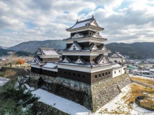 A majestic view of Ozu Castle in Ehime, with its traditional wooden keep beautifully covered in winter snow.