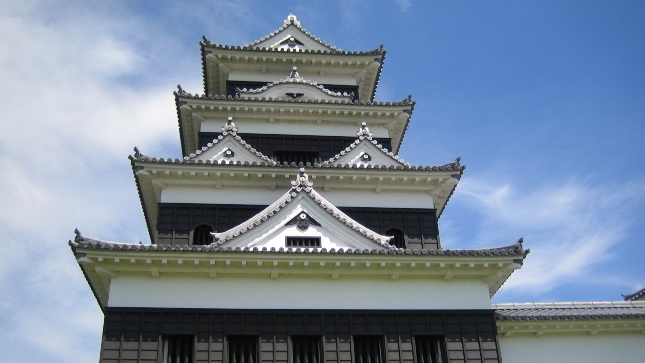 Ozu Castle’s magnificent keep, painstakingly reconstructed using traditional wooden techniques, stands tall against a clear blue sky.