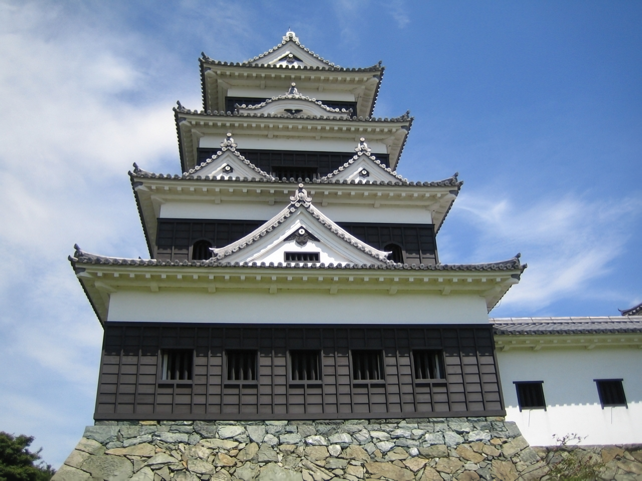 Ozu Castle’s magnificent keep, painstakingly reconstructed using traditional wooden techniques, stands tall against a clear blue sky.