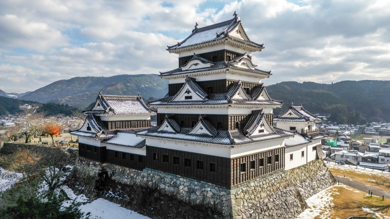 A majestic view of Ozu Castle in Ehime, with its traditional wooden keep beautifully covered in winter snow.