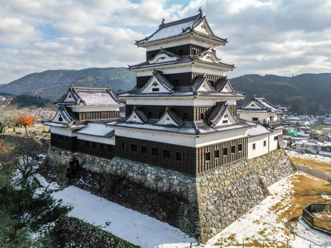 A majestic view of Ozu Castle in Ehime, with its traditional wooden keep beautifully covered in winter snow.