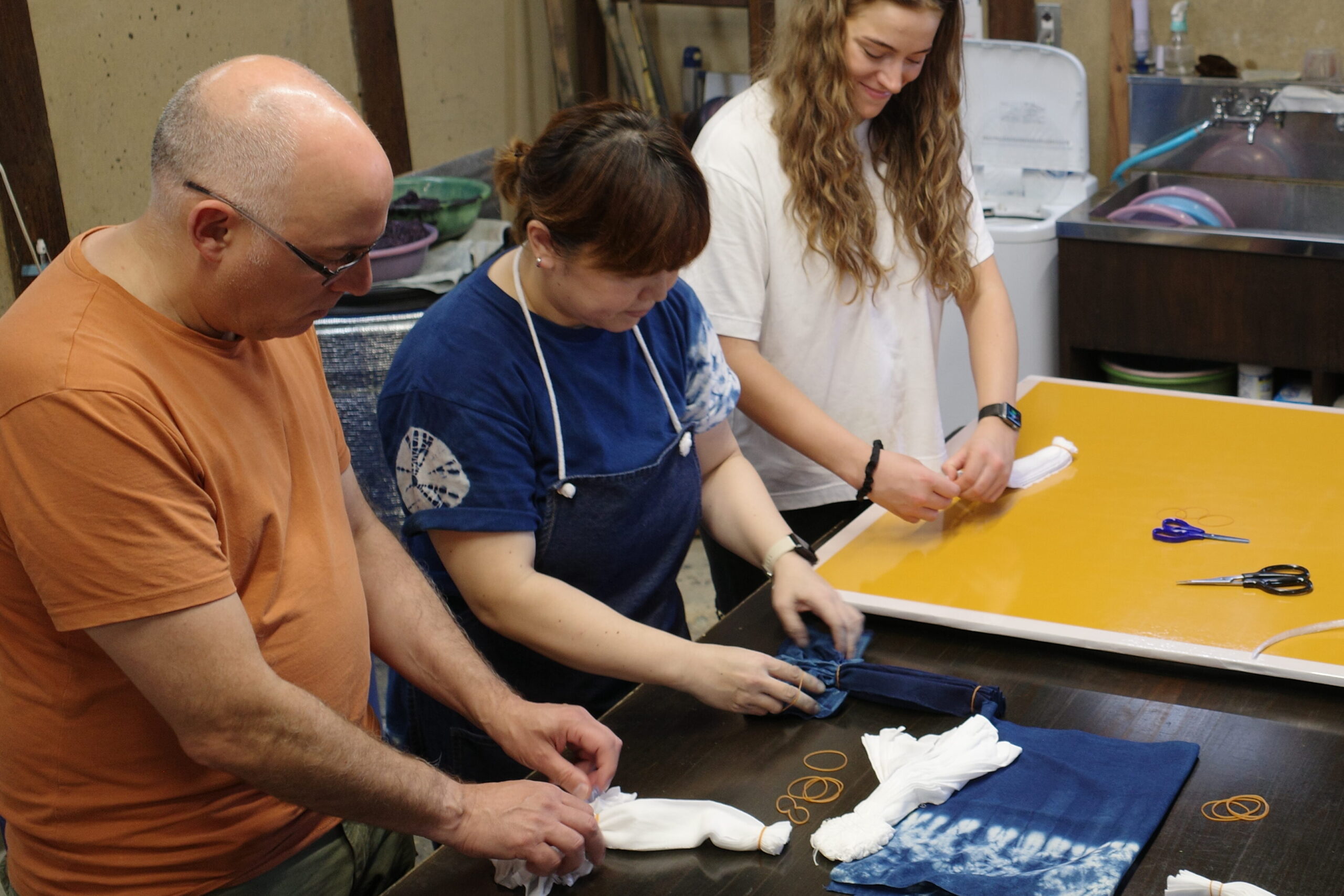 A craftsperson at Yamamuichi Kobo shows visitors how to tie-dye items to get their desired outcome in Wakimachi, Tokushima