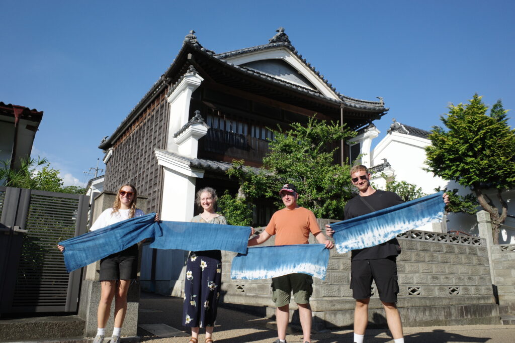 Travelers show off their indigo dyeing creations in front of a historical merchant house in Wakimachi.
