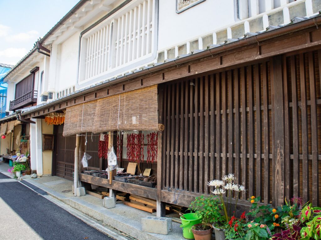 Dried chili peppers and baskets of local produce line a shopfront in Uchiko's historic district, where family-run stores sell handmade goods, crafts, and souvenirs.