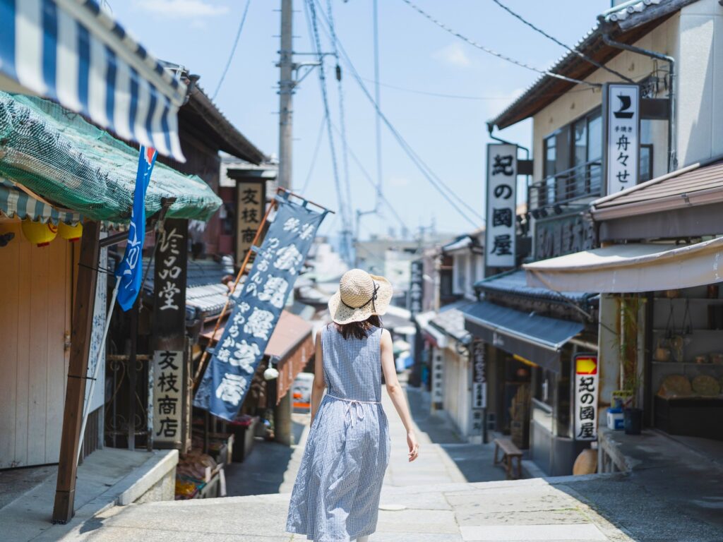 The shop-lined approach to Konpira-san, where worn stone paving, hand-painted banners, and souvenir stalls greet pilgrims long before the first step.