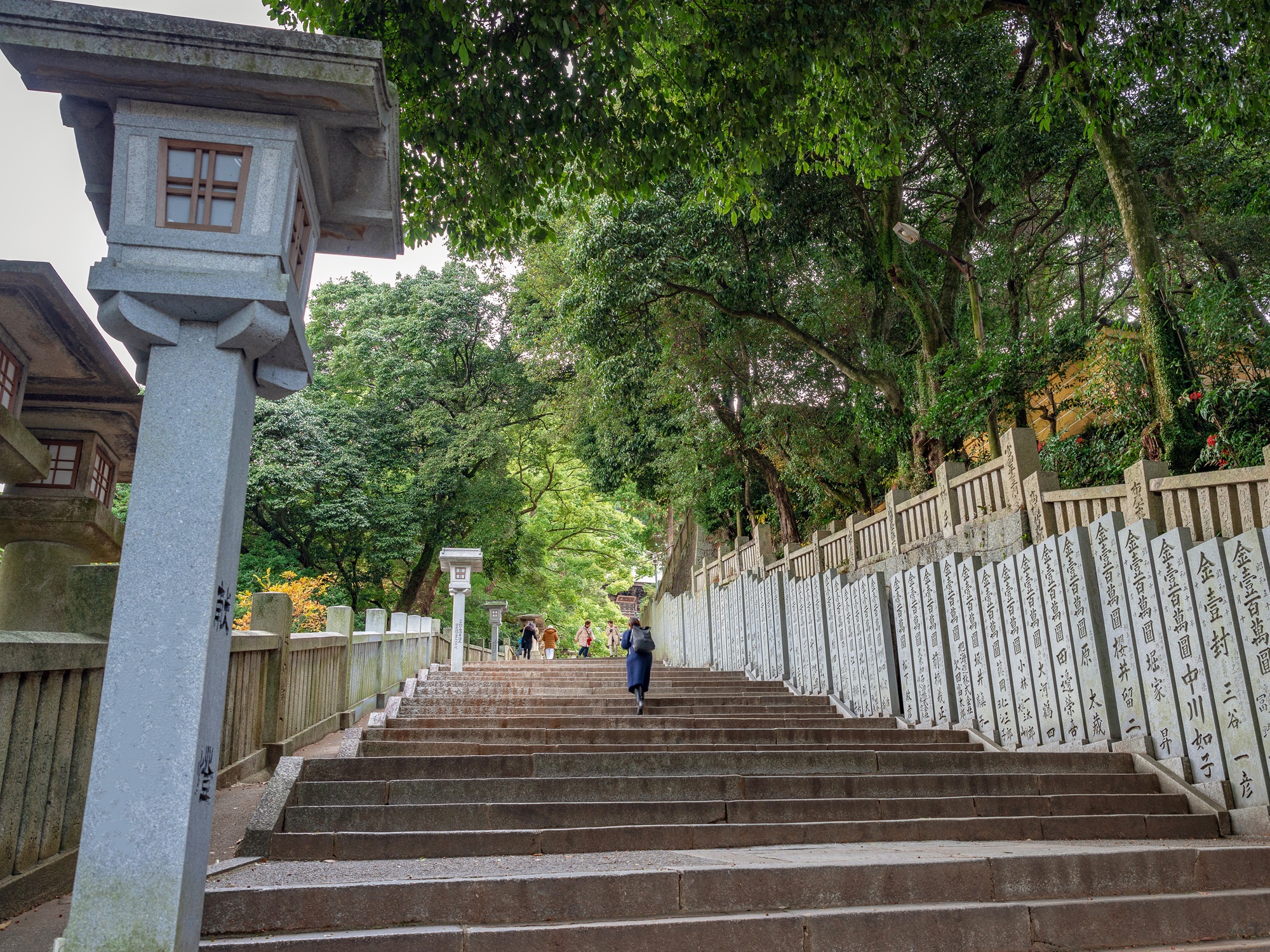 Rows of inscribed donation pillars line the climb, each stone recording a gift to the shrine — a thousand years of gratitude, carved and standing.