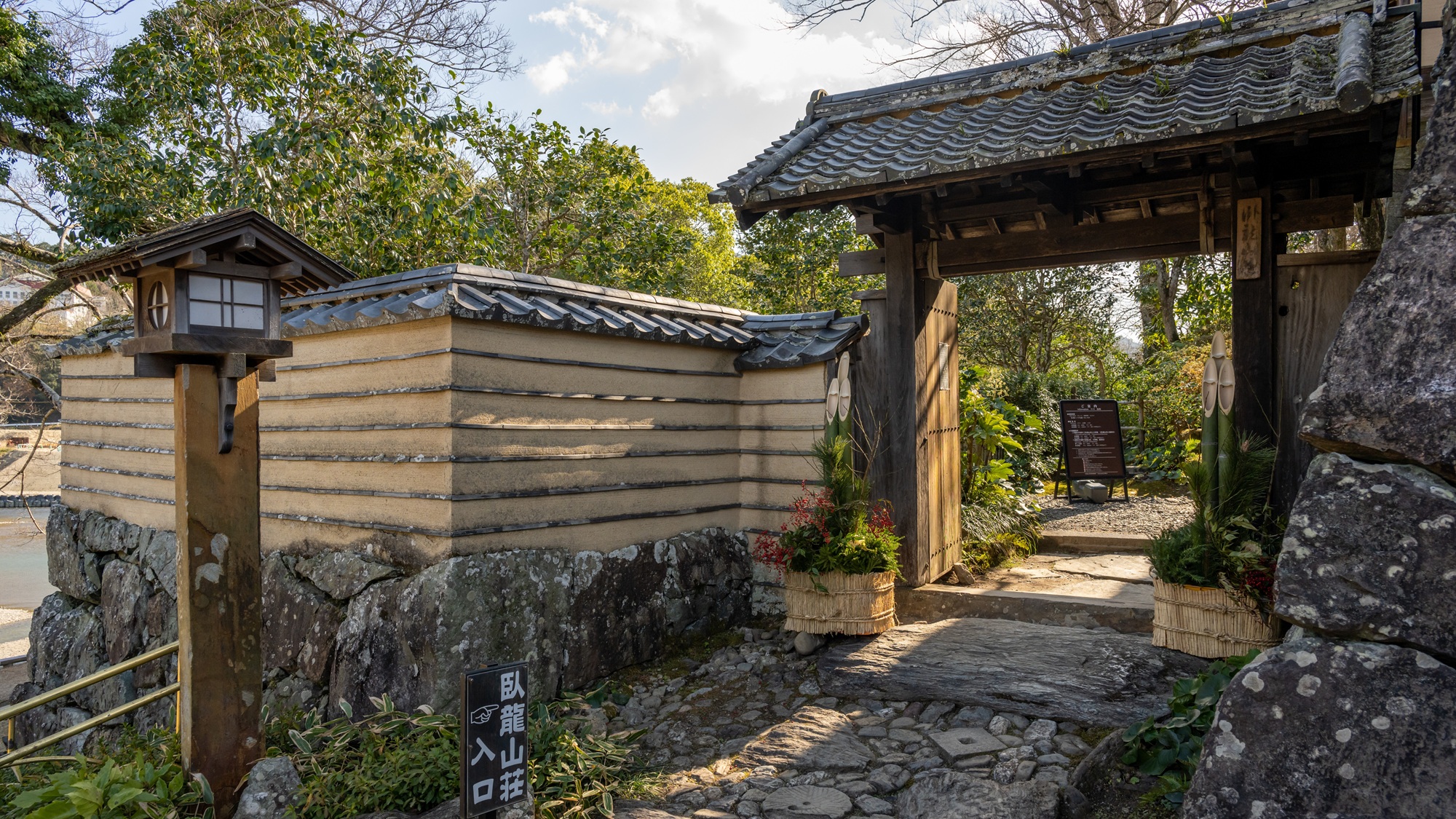 The entrance gate to Garyu Sanso, with its earthen wall, tiled roof and stone-paved approach