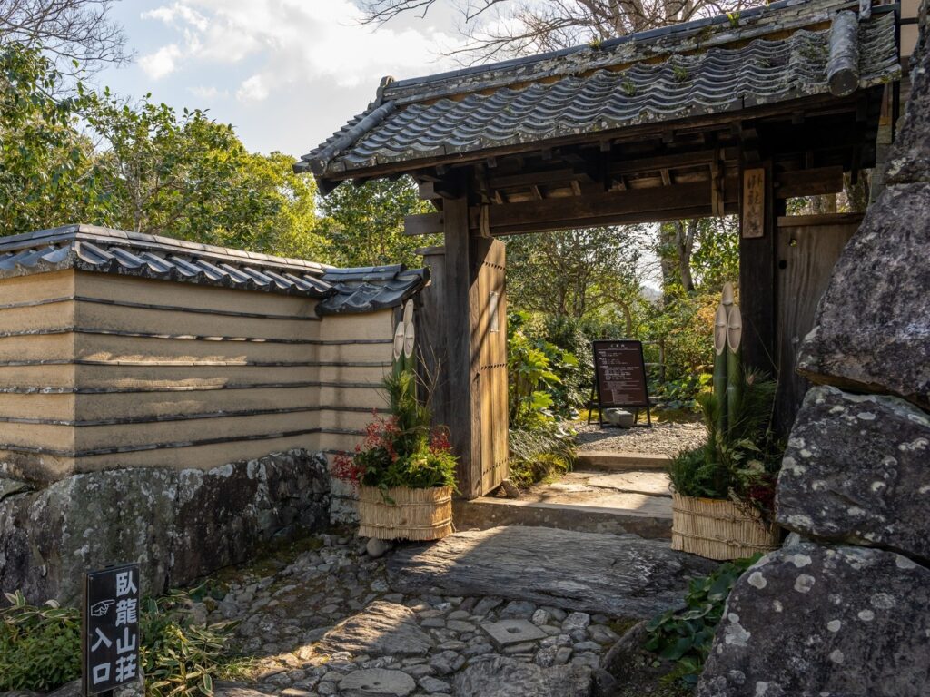 The entrance gate to Garyu Sanso, with its earthen wall, tiled roof and stone-paved approach