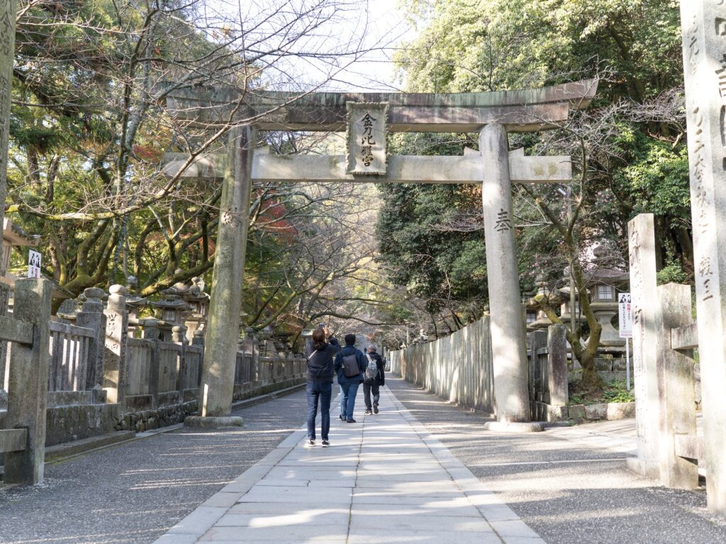 The great stone torii marks where the everyday ends: past this gate the path belongs to Ōmononushi, god of the sea and seafarers.