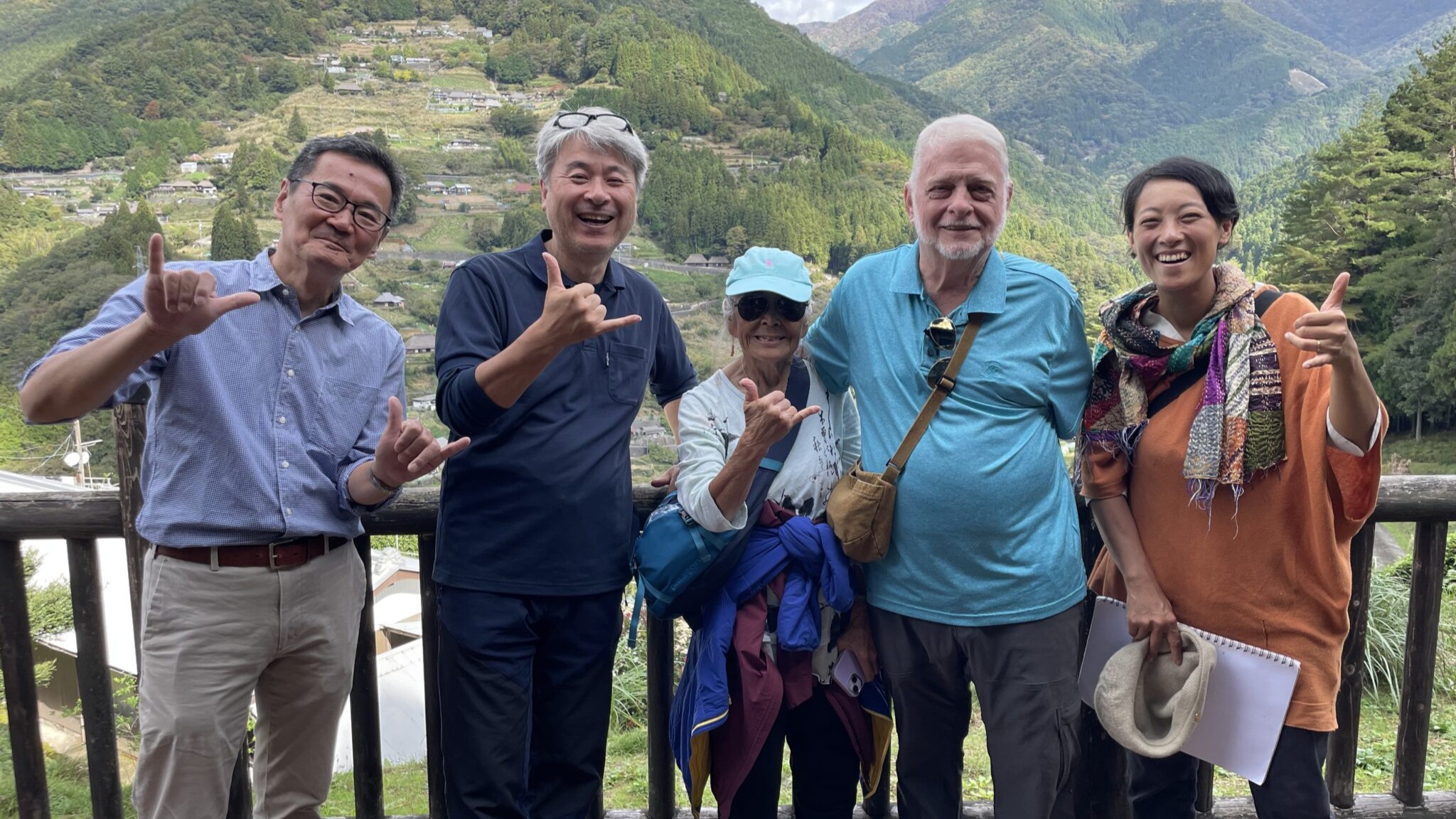 Local guides and overseas guests smiling together above a mountain village in Shikoku