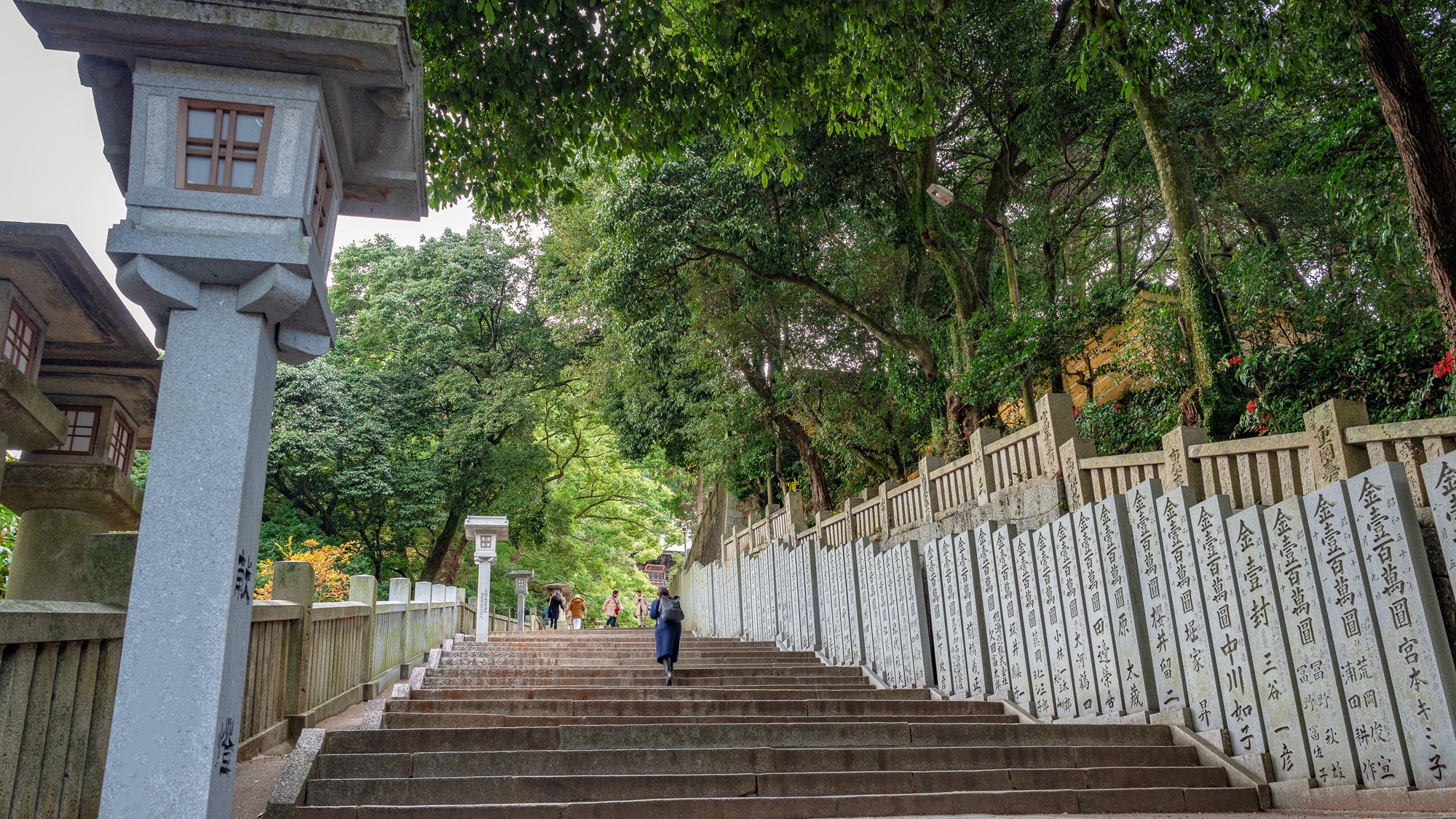 Rows of inscribed donation pillars line the climb, each stone recording a gift to the shrine — a thousand years of gratitude, carved and standing.