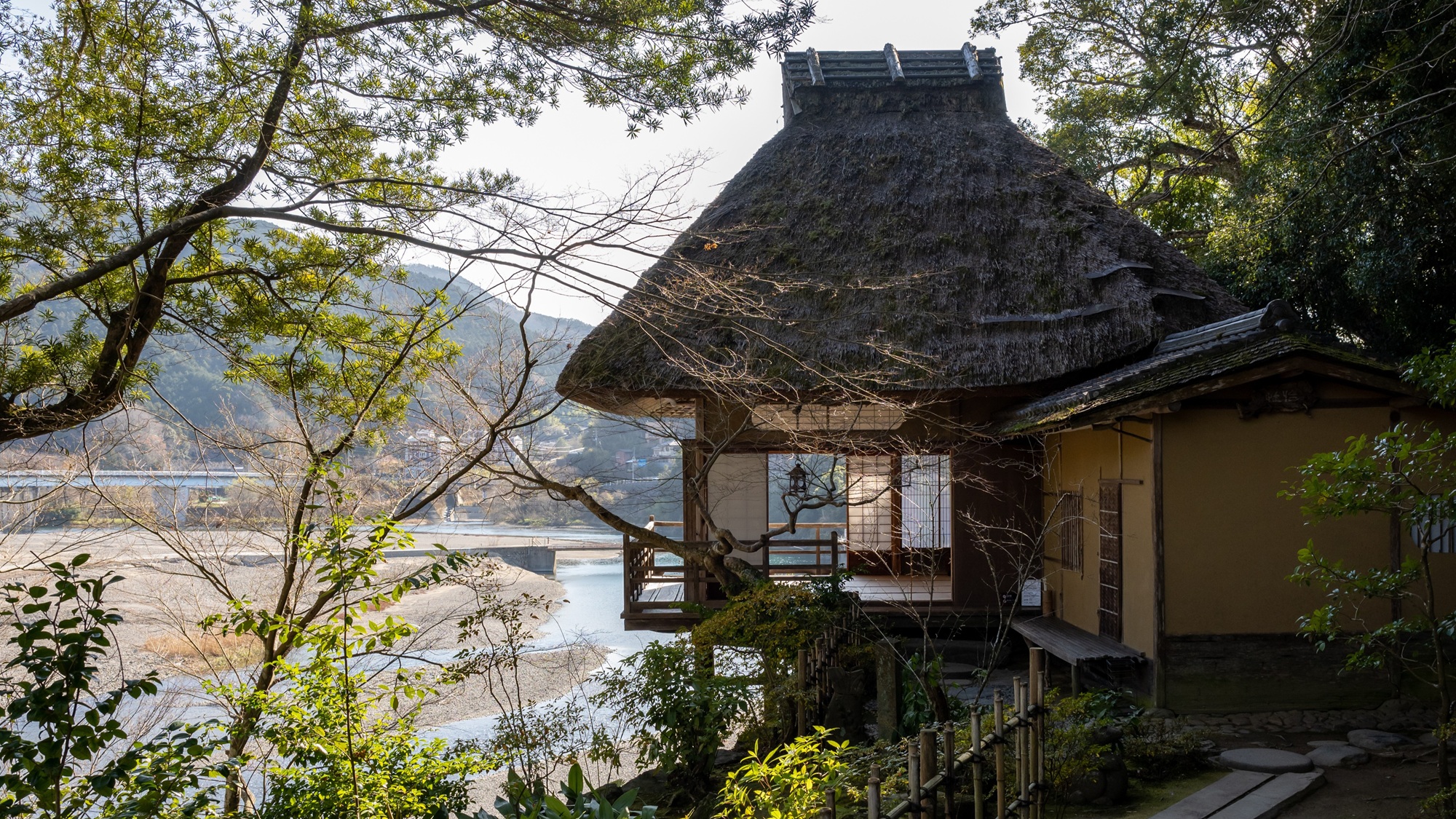 The thatched teahouse Furo-an, its veranda looking out over the Hijikawa River and the town of Ozu