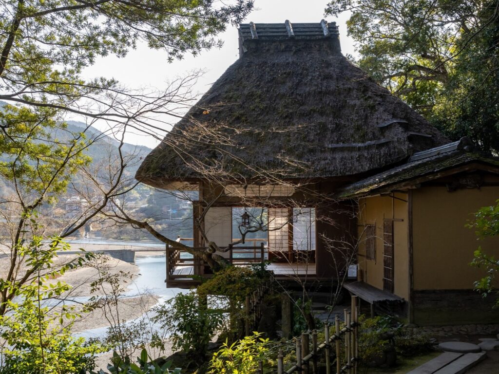 The thatched teahouse Furo-an, its veranda looking out over the Hijikawa River and the town of Ozu