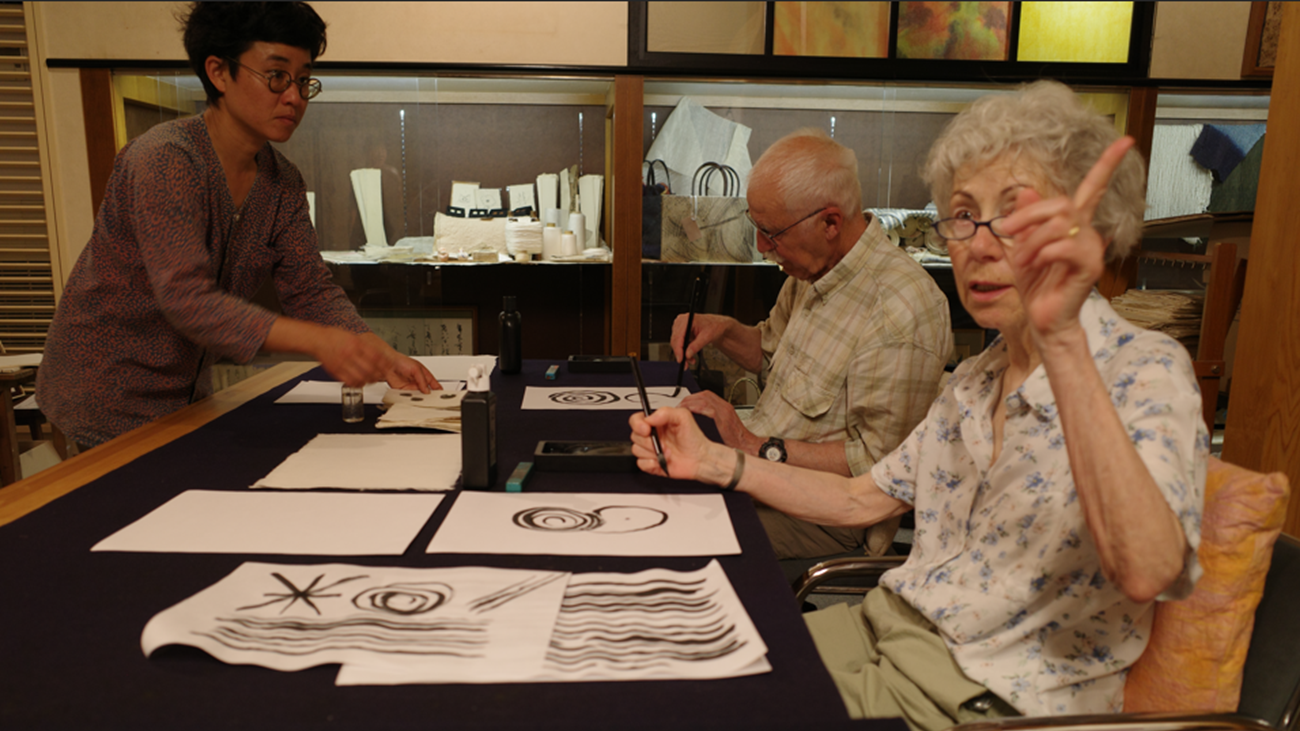 Guests practicing Japanese calligraphy on handmade washi paper with an instructor