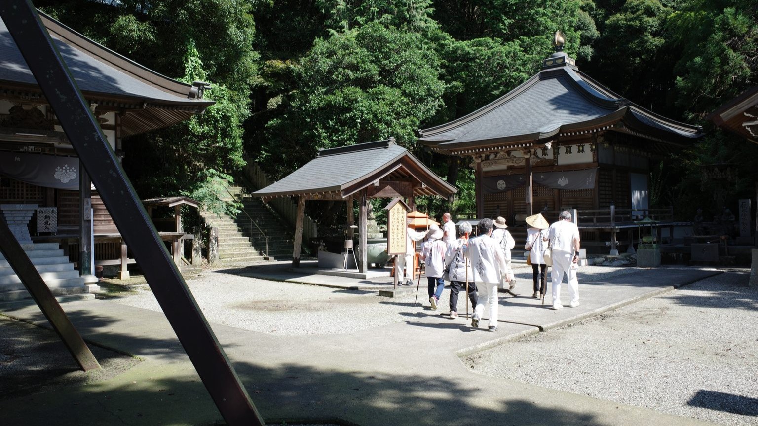 Pilgrims in white clothing walk toward Gokuraku-ji's main hall. The hall is at the top of 42 stairs, visible at the top left of the photo.