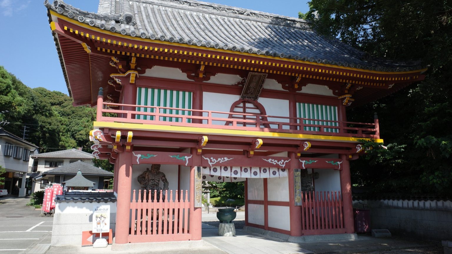 The vermillion gate of Gokuraku-ji rises above country houses in Tokushima.