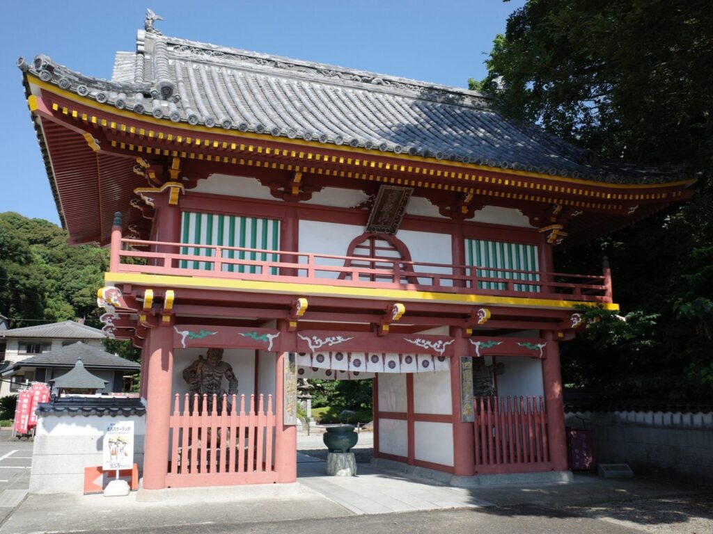 The vermillion gate of Gokuraku-ji rises above country houses in Tokushima.