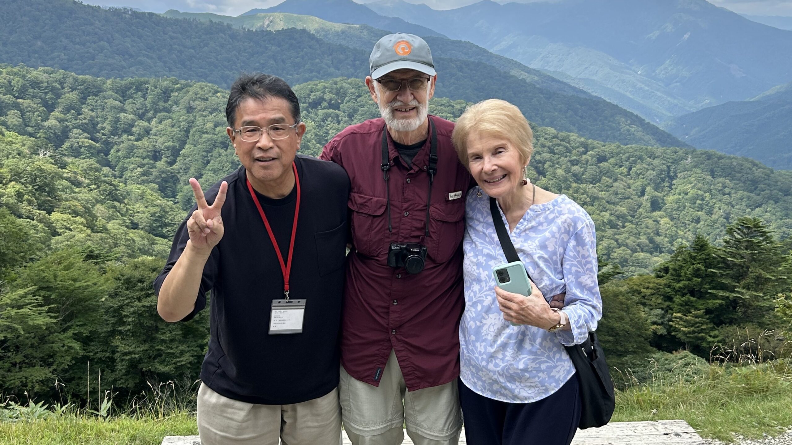 Guests and their private driver at a mountain viewpoint overlooking forested ridges in Shikoku
