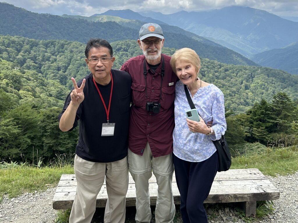 Guests and their private driver at a mountain viewpoint overlooking forested ridges in Shikoku