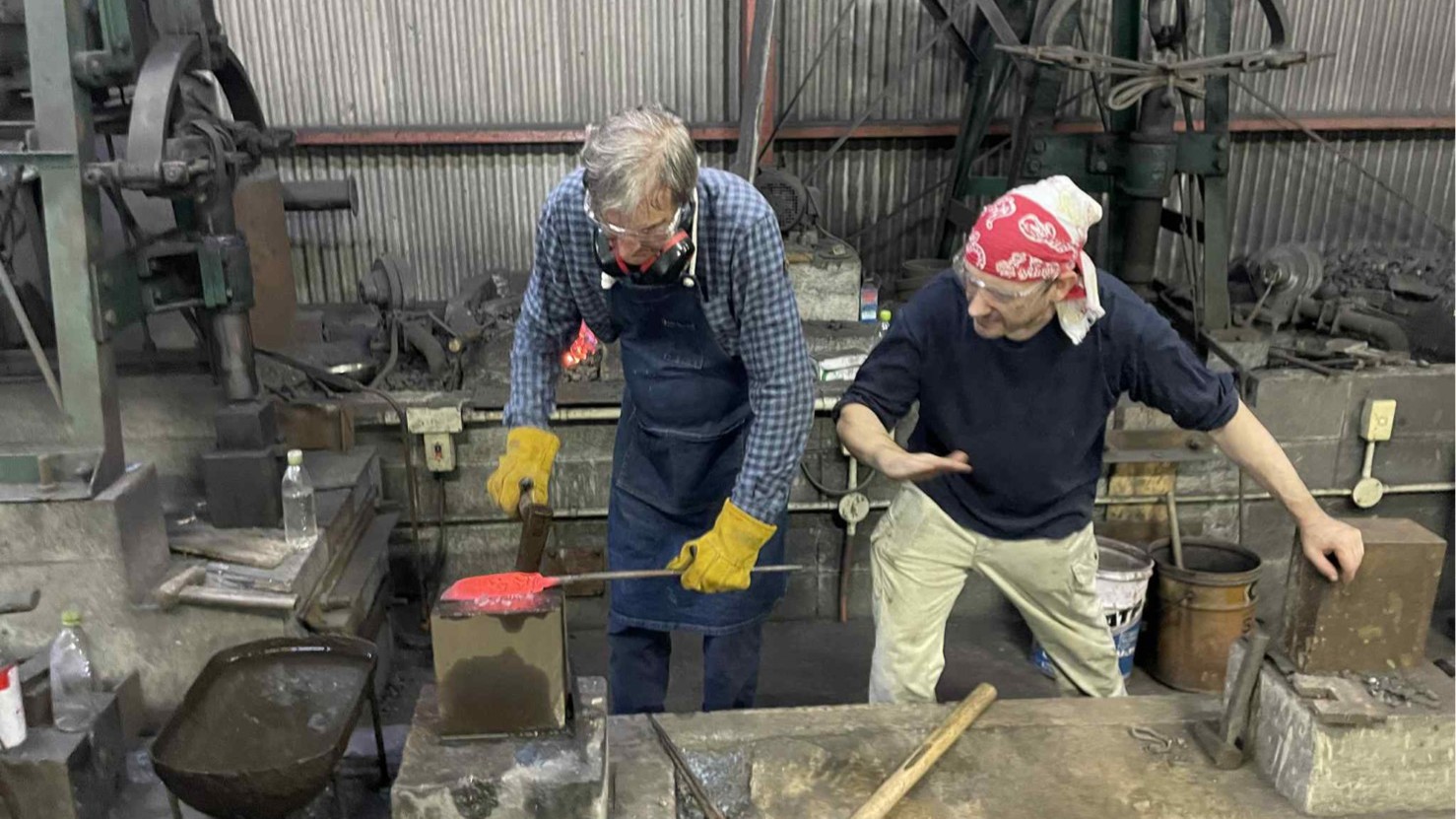 A guest shaping red-hot steel on an anvil with a blacksmith at Kobo Kurogane forge in Nishitosa, Kochi