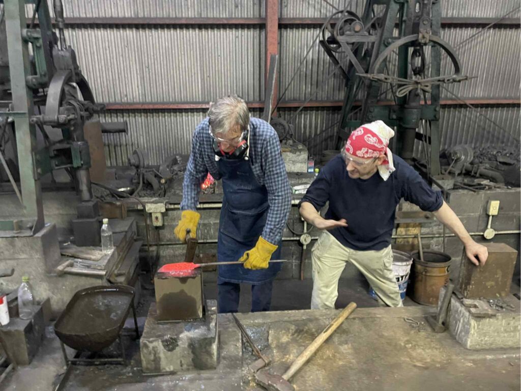 A guest shaping red-hot steel on an anvil with a blacksmith at Kobo Kurogane forge in Nishitosa, Kochi