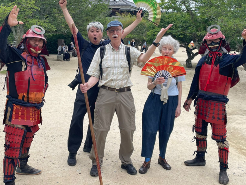 Guests posing with samurai armor performers on the grounds of Matsuyama Castle, Ehime